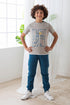 Child wearing a gray t-shirt with blue pants and white sneakers, standing indoors.