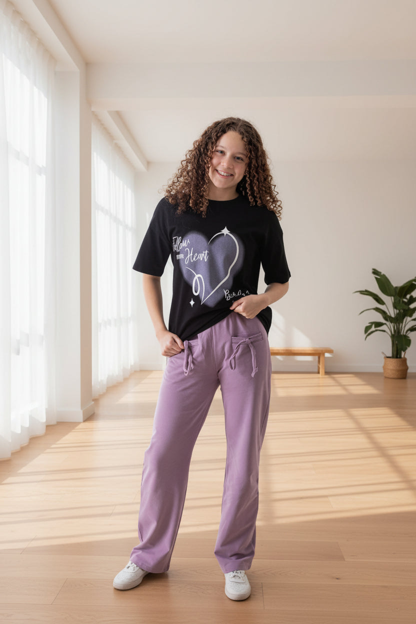 Woman wearing a black t-shirt and purple pants with Rama Kids Wear logo in the corner.