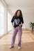 Woman wearing a black t-shirt and purple pants with Rama Kids Wear logo in the corner.